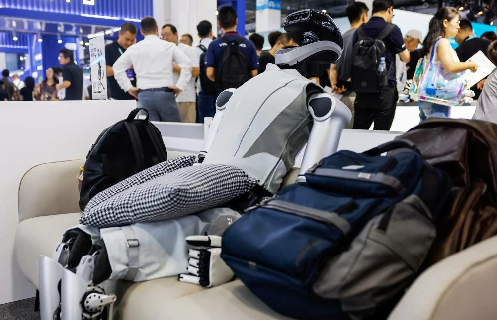 A Robotera L7 humanoid robot sits on a sofa next to backpacks at the company's booth at the 2026 World Robot Conference, in Beijing, China, August 20, 2026. (Reuters)