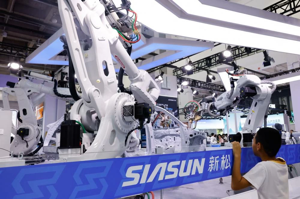 A boy looks at industrial robots installed as a part of a car assembly line at Siasun booth at the 2026 World Robot Conference, in Beijing, China, August 19, 2026. (Reuters)