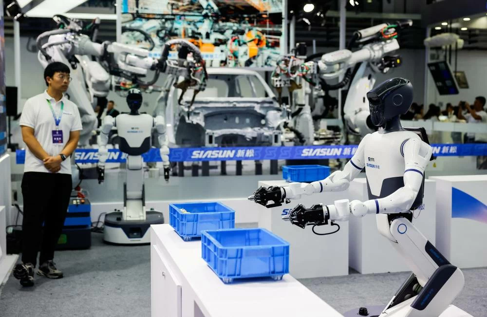 An employee looks on next to humanoid robots and industrial robot arms at Siasun booth at the 2026 World Robot Conference, in Beijing, China, August 19, 2026. (Reuters)