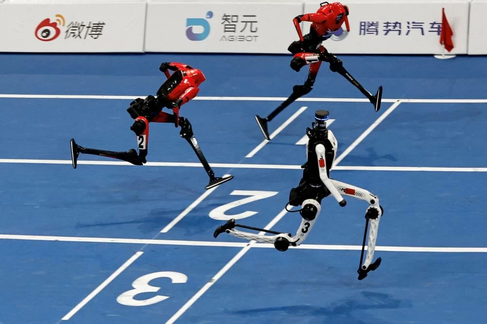 A Tiangong Ultra humanoid robot crosses the finish line in 8.86 seconds, next to Honor humanoid robots, during a 100m large-size group semifinal race, at the 2026 World Humanoid Robot Games at the National Speed Skating Oval in Beijing, China, August 25, 2026. REUTERS