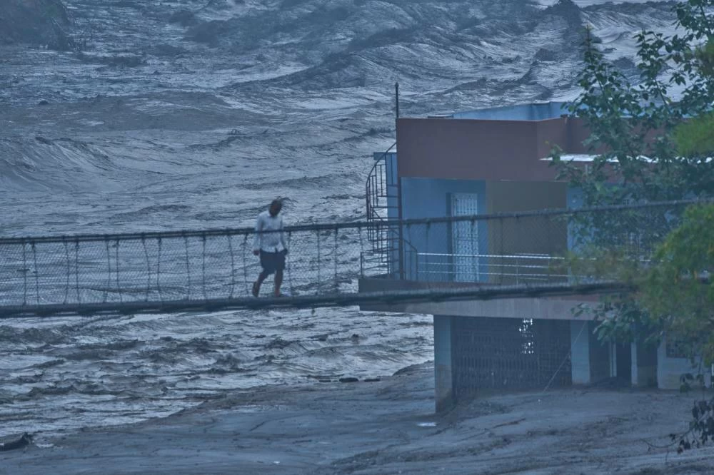 A resident walks across a bridge at the swollen Trishuli river in Galchhi, Dhading District, Nepal, Sunday, Aug. 30, 2026. AP