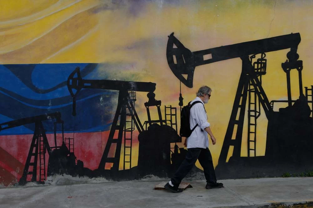A pedestrian walks past a mural featuring oil wells in Caracas, Venezuela. In a social media post, Trump described the agreement as "THE BIGGEST OIL DEAL IN WORLD HISTORY" and said it would provide access to 65 billion barrels of oil reserves. AP