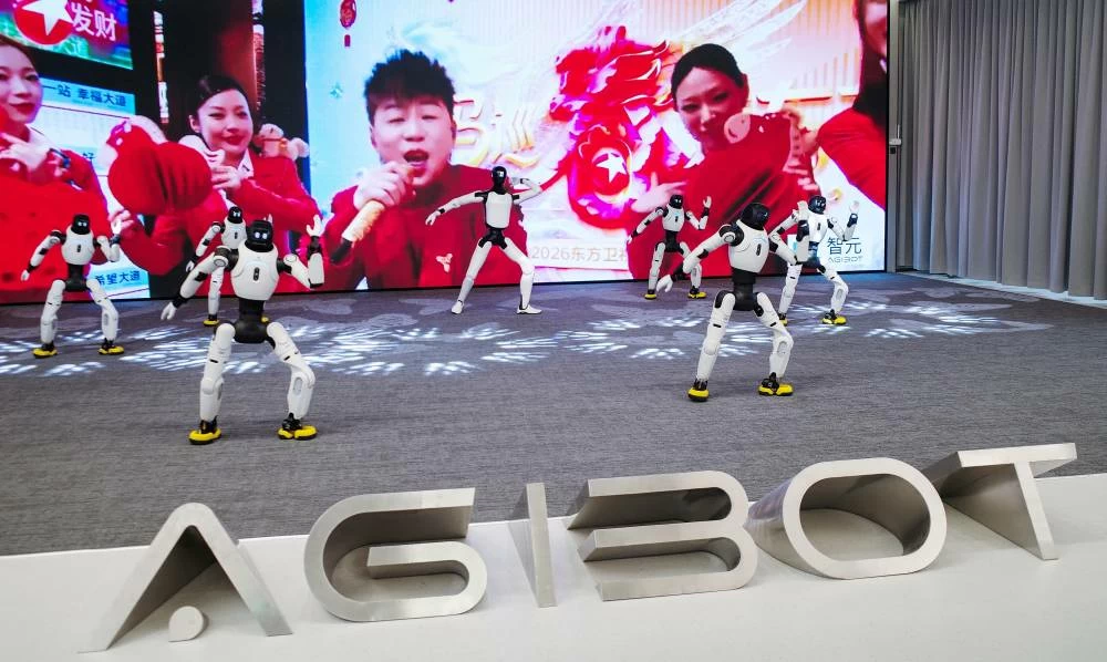 Agibot humanoid robots dance in front of a giant screen at the company's headquarters in Shanghai, China, April 20, 2026. (Reuters)