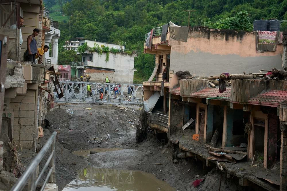 Survivors look out from their flash flood-damaged house as they take a break from cleaning in Devighat, Nuwakot district, Nepal. AP