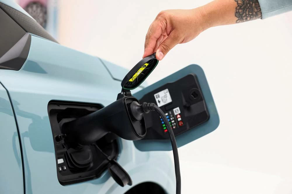 An employee touches the electric charging plug of new Dacia Spring electric car, of which production has been moved from China to Europe, displayed during a presentation in Aubervilliers near Paris, France, September 2, 2026. (Reuters)