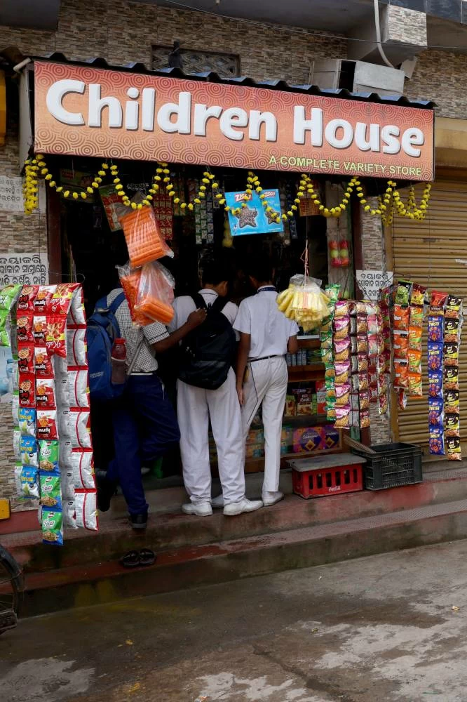 Schoolchildren stand at the front of a grocery shop in Bhubneshwar, Odisha, India, September 18, 2026. (Reuters)