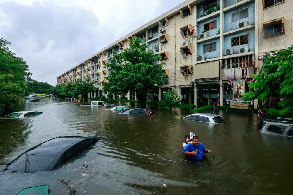 People wade through a flooded street during heavy rain in Bangkok, Thailand. REUTERS