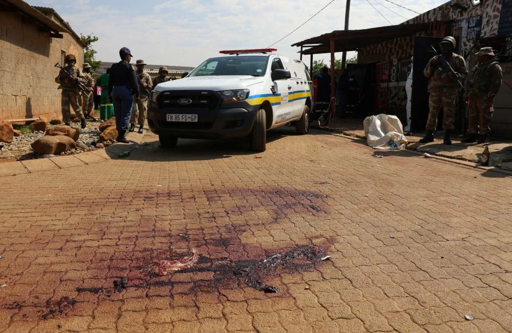 Blood stains on the ground next to an emergency vehicle at the site of a deadly shooting at a tavern in Wedela township, southwest of Johannesburg, South Africa, September 27, 2026. REUTERS
