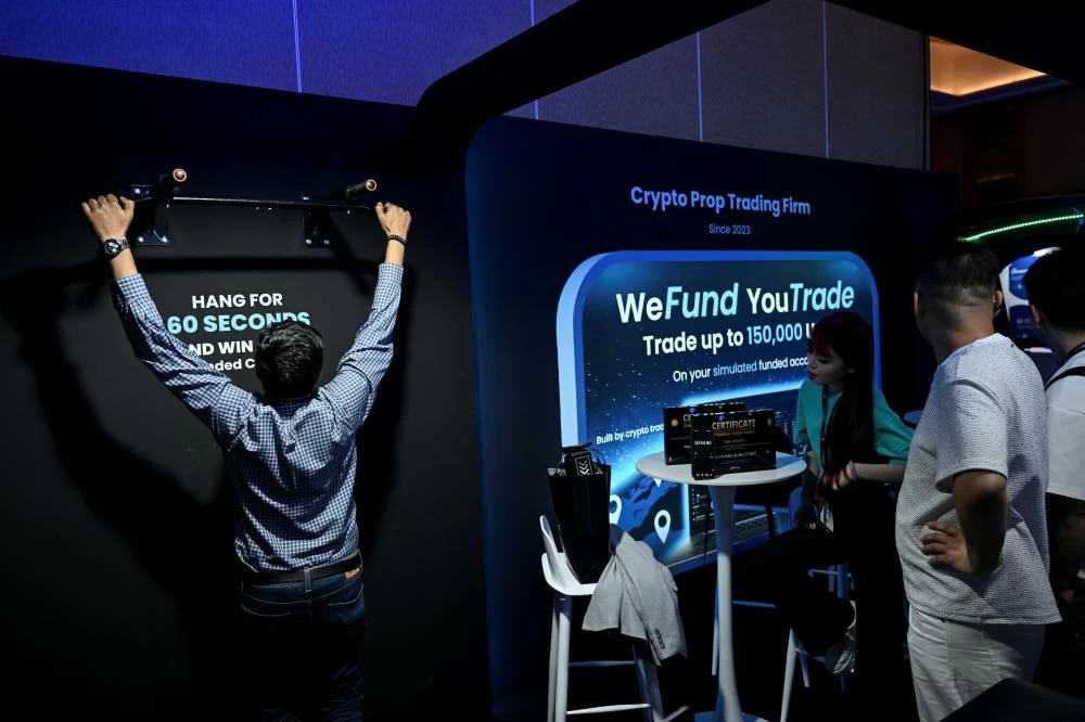 A man hangs on a pull-up bar as part of a competition at the Bitfunded booth during TOKEN2049 crypto conference in Singapore October 7, 2026. REUTERS/Caroline Chia