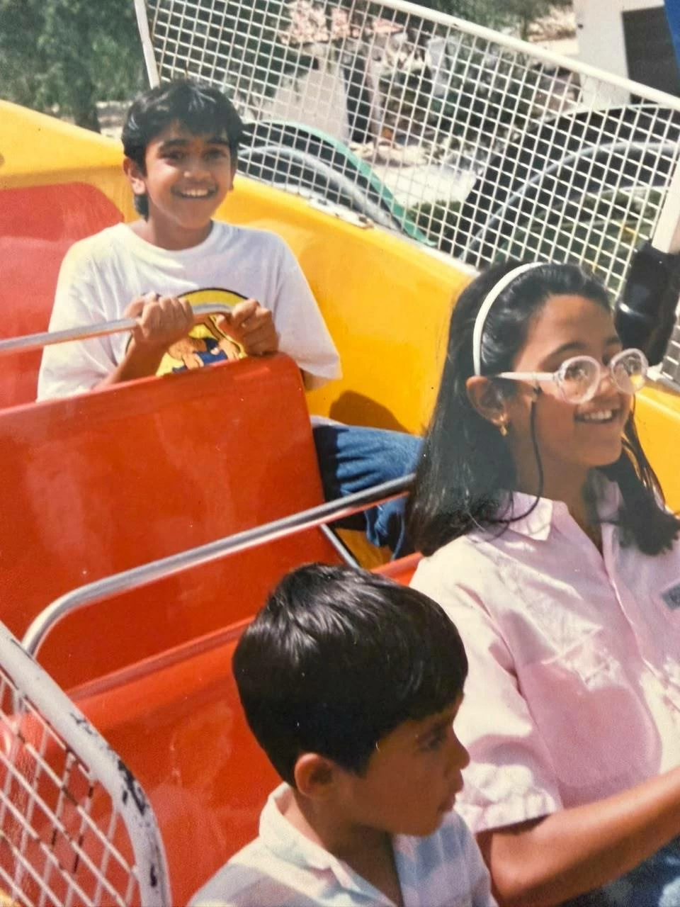 Rego, sitting at the back of a ride, with his cousin and sister, at a UAE amusement park.